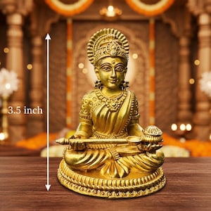 May include: A golden statue of a seated female figure, approximately 3.5 inches tall. The statue features intricate details in its design, including ornate jewelry and a decorative headdress. The figure is holding objects in her hands, and the base is adorned with a detailed pattern.