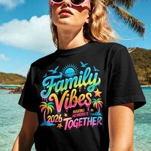 May include: Black t-shirt with a colorful graphic that reads "Family Vibes Making Memories Together 2026." The design includes a sun, birds, palm trees, and stars in shades of blue, yellow, pink, and green.