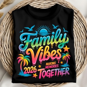 May include: Black t-shirt with a colorful graphic that reads "Family Vibes 2026 Making Memories Together." The design includes a sun, birds, palm trees, and stars, with a rainbow color scheme. The shirt is folded on a woven basket.