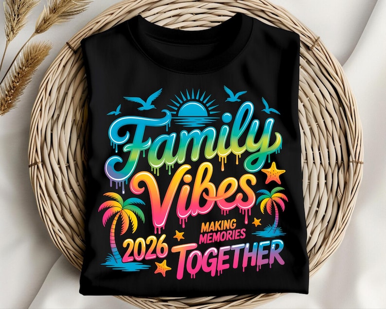 May include: Black t-shirt with a colorful graphic that reads "Family Vibes 2026 Making Memories Together." The design includes a sun, birds, palm trees, and stars, with a rainbow color scheme. The shirt is folded on a woven basket.