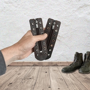 May include: Two dark brown leather boot lace-up zipper inserts featuring a central zipper closure and two vertical rows of silver-toned metal eyelets along the edges. These accessories are designed to be attached to boots for a modified look.