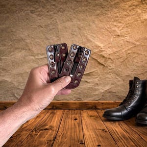 May include: Two dark brown leather boot lace zipper inserts featuring a central black zipper and two vertical rows of silver-toned metal eyelets along the edges, designed to be attached to the front of a pair of dark brown leather lace-up boots.