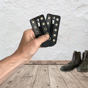 May include: Two black leather boot lace-in zipper inserts featuring silver-toned YKK zippers and gold-toned metal eyelets arranged in two vertical rows on each piece. The inserts are designed to be laced into boots for a quick-fastening closure.