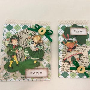 May include: Two St. Patrick's Day themed tags. One features dancing figures on a shamrock with the text "happy jig". The other has a figure holding a shamrock with the text "KISS ME". Both have green and white plaid backgrounds.