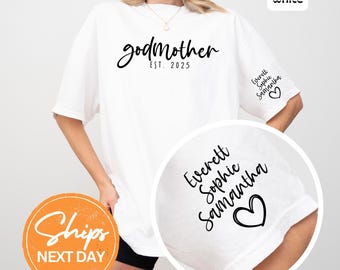 May include: White t-shirt with the word "godmother" in a script font and the text "EST. 2025". The sleeve features the names "Everett Sophie Samantha" and a heart symbol. A casual, comfortable style.