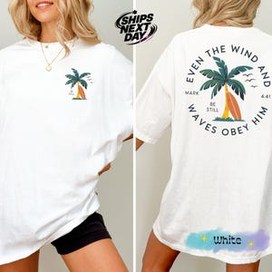 a woman wearing a white shirt with a palm tree on it