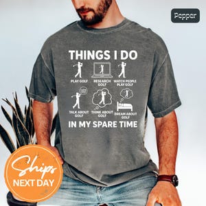 May include: Gray t-shirt with the text "THINGS I DO" and illustrations of golf-related activities. The shirt includes phrases like "Play Golf," "Research Golf," and "Dream About Golf." The shirt also has the text "IN MY SPARE TIME."