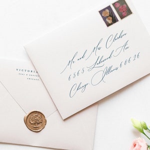 Peut inclure: Deux enveloppes blanches avec une calligraphie bleue les adressant à "Mr. and Mrs. Clarkson" avec un sceau de cire doré sur l'enveloppe du dessus. L'adresse comprend un numéro de rue, un nom de rue, une ville et un état. L'enveloppe du bas porte le texte "VICTORIA MADISON" imprimé au dos.
