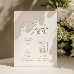 May include: A cream-colored card with the words "Signature Drinks" in elegant script. Below are illustrations of an Espresso Martini and an Old Fashioned cocktail. White flowers are in the background.