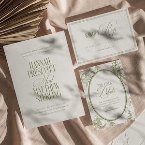 May include: Elegant wedding invitation suite featuring a main invitation with names "Hannah Prescott And Matthew Sterling", RSVP card, and details card. The text is in a green hue on a white background. The suite is arranged on a pink fabric.