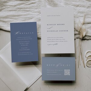 Op de afbeelding: Een blauwe en witte huwelijksuitnodigingsset met een eenvoudig ontwerp. De uitnodigingskaart bevat de namen "Kinsley Moore" en "Nicholas Connor" in een serif-lettertype. De detailkaart bevat de datum, tijd en locatie van de bruiloft. De RSVP-kaart heeft een QR-code en het websiteadres "kinsleyandnick.com".