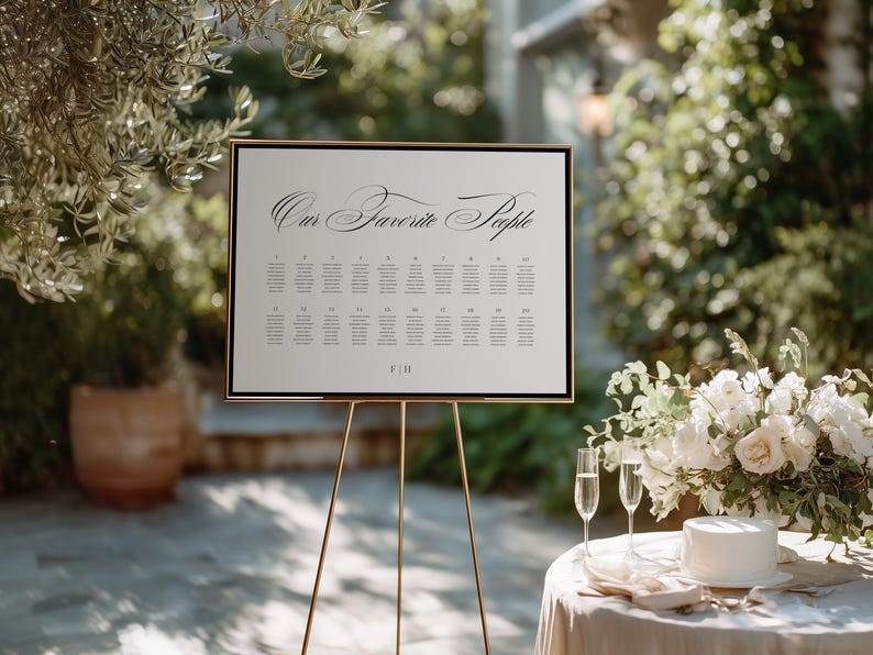 May include: A rectangular wedding seating chart sign with a black frame, featuring the text "Our Favorite People" in a black script font at the top, followed by a grid of twenty numbered tables with guest names and the initials "F|H" at the bottom.