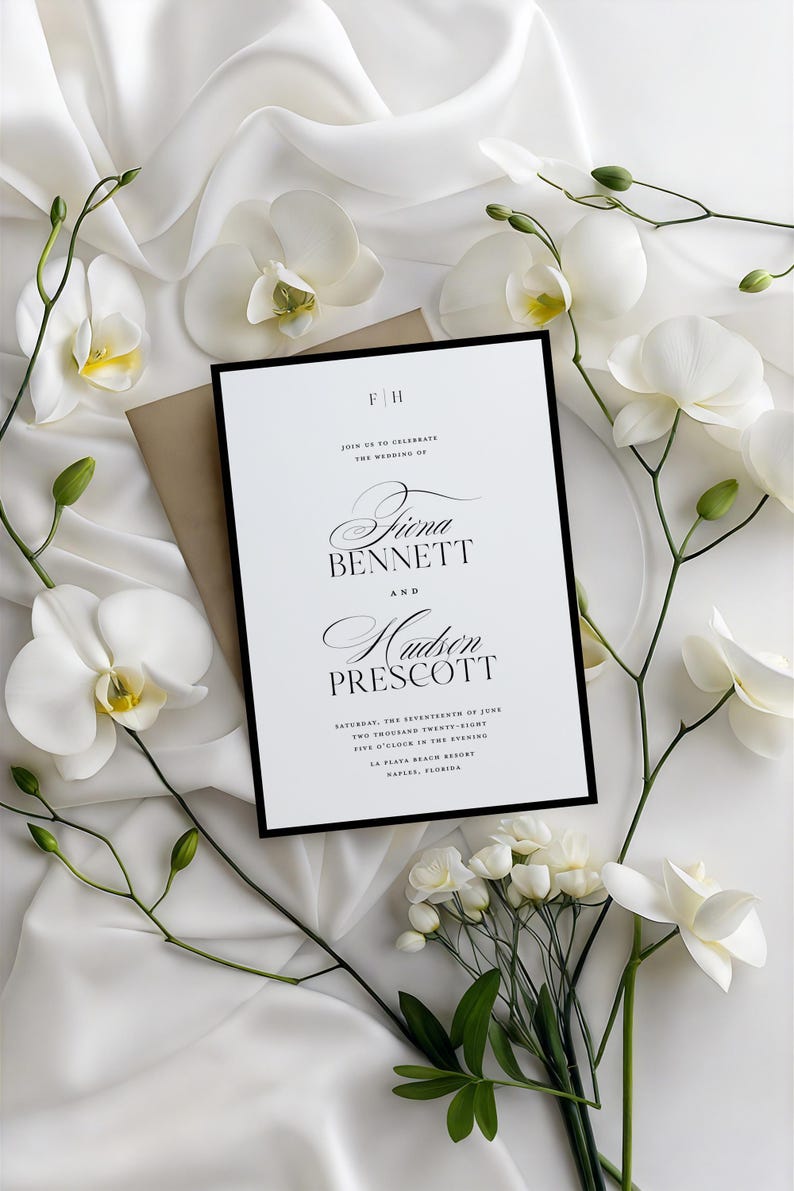 May include: Wedding invitation with a black border, featuring the names Fiona Bennett and Hudson Prescott. The invitation is surrounded by white orchids and a tan envelope, set against a white, silky background.