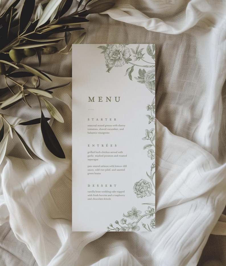 May include: A wedding menu card with a floral design in soft green. The word "MENU" is at the top, with a list of courses below: Starter, Entrees, and Dessert. The card is on a white cloth with olive branches.