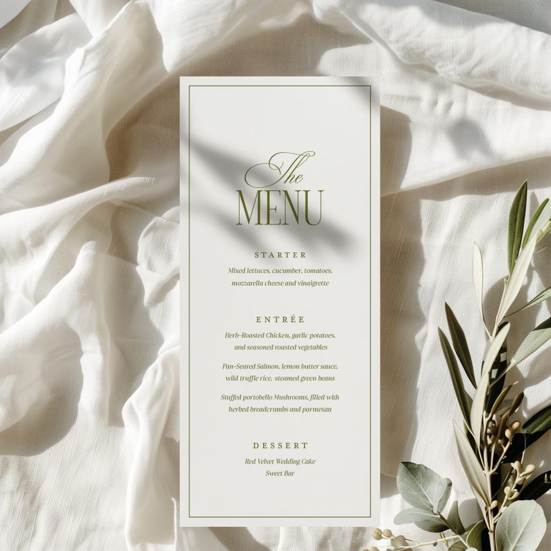 May include: A formal menu card with a white background and a green border. The text "The MENU" is at the top, followed by the menu items: Starter, Entr&eacute;e, and Dessert. The menu is displayed on a white cloth with greenery.