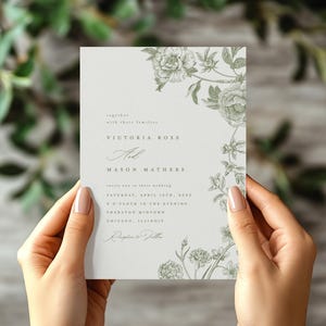May include: A rectangular wedding invitation card on white paper featuring a delicate sage green botanical illustration of flowers along the right side. The text reads: Together with their families, Victoria Ross and Mason Mathers invite you to their wedding, Saturday, April 13th, 2024, 5 o'clock in the evening, Sheraton Midtown, Chicago, Illinois, Reception to Follow.