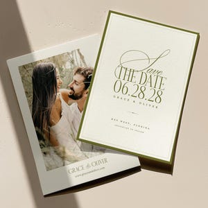 May include: Two wedding announcement cards. One card features a photo of a couple, the other has the text "Save the Date 06.28.28 Grace & Oliver" in olive green. The cards are on a light beige surface.