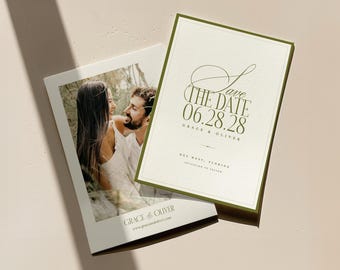 May include: Two wedding announcement cards. One card features a photo of a couple, the other says "Save the Date 06.28.28" in olive green script. The cards are on a light beige surface.
