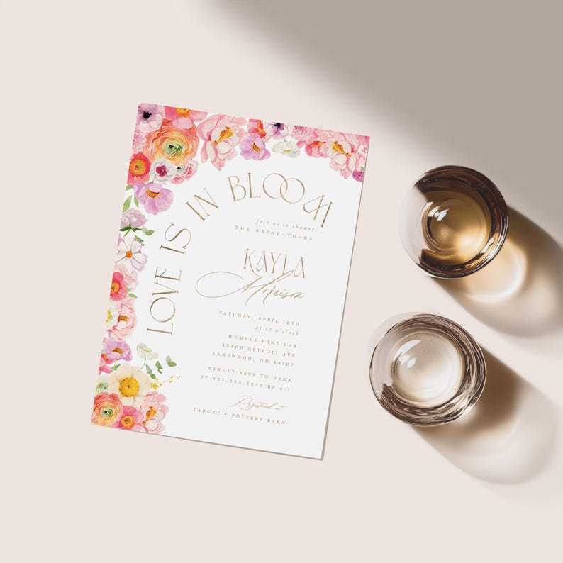 May include: A bridal shower invitation with floral accents and the text "Love is in Bloom" and "Kayla Melissa". The invitation features a watercolor floral design in pink, peach, and yellow. Two clear, round glasses are also in the image.
