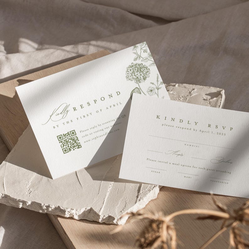 May include: Two white rectangular RSVP cards with sage green botanical illustrations. The cards feature the text KINDLY RESPOND BY THE FIRST OF APRIL, a QR code, and lines for guest names and meal selections including steak, fish, and vegetarian options.