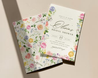 Könnte beinhalten: Eine rechteckige Einladung zur Brautparty mit passendem Umschlag, verziert mit einem Aquarell-Blumenmuster in Rosa, Gelb und Violett. Der Text lautet: Love is in bloom, please join us for Olivia's Bridal Shower, August 23 at 1pm.