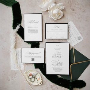 May include: A wedding stationery suite with white cards and black borders, featuring elegant calligraphy. The set includes an invitation, RSVP card, and details card. Complemented by a dark green velvet ribbon, white flowers, and a decorative tray.