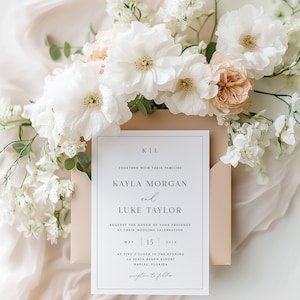 Pu&ograve; includere: Un invito di nozze con i nomi Kayla Morgan e Luke Taylor, datato 15 maggio 2026. L'invito &egrave; circondato da fiori bianchi e pesca, con uno sfondo morbido e dai toni neutri. Il design &egrave; semplice ed elegante.