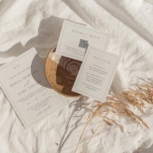 Pu&ograve; includere: Invito di nozze composto da tre biglietti dal design minimalista. I biglietti includono dettagli come "Kindly RSVP", "Details" e i nomi "Kayla Morgan" e "Luke Taylor". Il set &egrave; disposto su una superficie strutturata bianco sporco con un piatto decorativo ed erba secca.