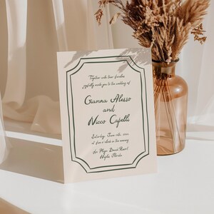 May include: A cream-colored wedding invitation with black and green lettering. The invitation reads "Together with their families joyfully invite you to the wedding of Gianna Alesso and Nicco Capelli Saturday, June 12th, 2023 at five o'clock in the evening The Playa Beach Resort Naples, Florida"