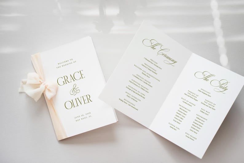 Pode incluir: Papelaria de casamento com um programa e um livreto. O livreto &eacute; amarrado com uma fita creme. O programa aberto mostra os detalhes da cerim&ocirc;nia e da festa. O texto inclui os nomes "Grace & Oliver" e a data.