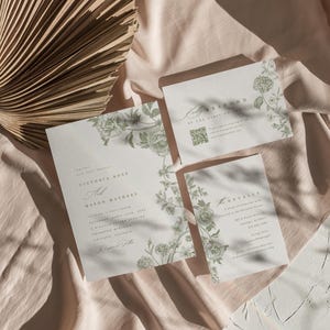 May include: A set of three white wedding invitation cards featuring green floral illustrations and black text. The main invitation lists Victoria Ross and Mason Mathere, accompanied by a response card with a QR code and a details card for the event.