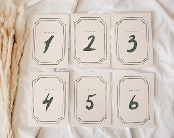 May include: Set of six table number cards. Each card features a cream background with a dark green border and number. The numbers 1 through 6 are displayed in a handwritten style. The words "TABLE NO." are printed at the top of each card.