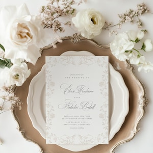 May include: A rectangular wedding invitation card with elegant black serif and script typography, featuring a delicate light gray floral border. The text reads: please join us for THE WEDDING OF Eloise Fontaine AND Nicholas Beckett SATURDAY, APRIL 15TH, 2028 AT FIVE O'CLOCK IN THE EVENING THE BELMONT HOUSE NAPA VALLEY, CALIFORNIA reception to follow.