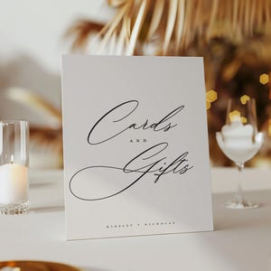 May include: White card with black calligraphy that reads "Cards and Gifts" with the names "Kimberly & Nicholas" at the bottom.