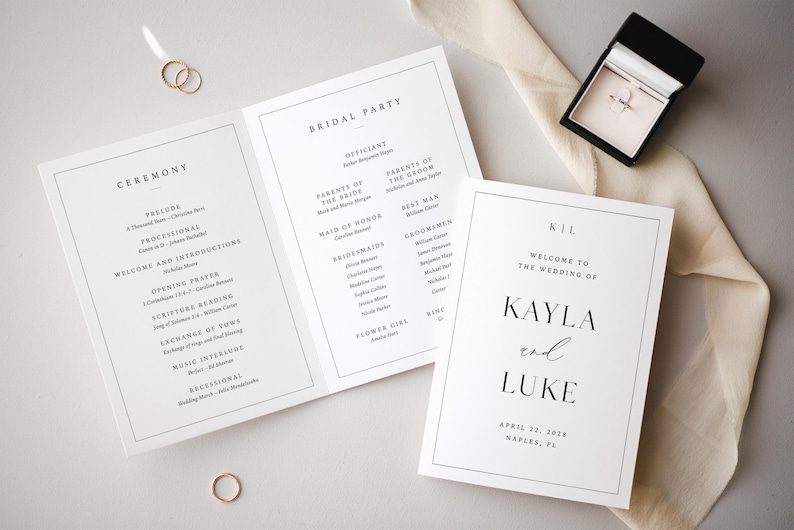 Op de afbeelding: Bruiloft briefpapier set met een drievoudig gevouwen programma, een welkomstbord en een ringdoosje. Het programma geeft de ceremonie details. Het welkomstbord toont de namen van het paar en de trouwdatum. Gouden ringen zijn ook zichtbaar.