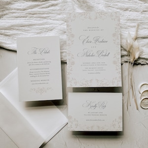 May include: A wedding invitation suite featuring a main invitation, a details card, and an RSVP card, all printed on white cardstock with light beige floral borders and elegant black serif and script typography, accompanied by a white envelope.