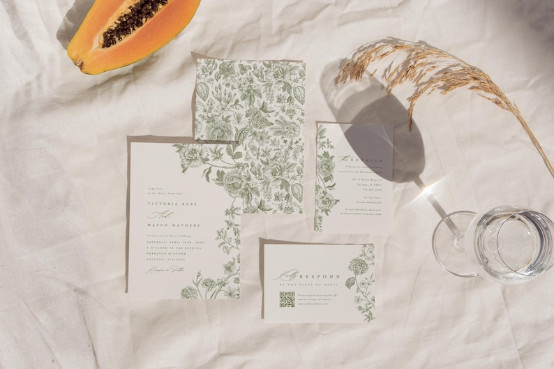 May include: A wedding stationery set featuring cream-coloured paper with sage green botanical illustrations. The set includes a main invitation, a smaller details card, an RSVP card with a QR code, and a square envelope liner with a floral pattern.