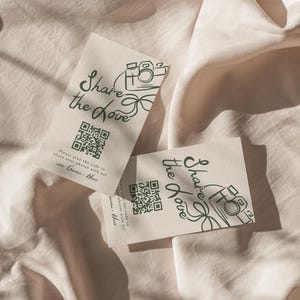 May include: Two white cards with a green camera icon and the text "Share the Love" printed on them. Each card has a QR code and instructions to scan the code to share photos.