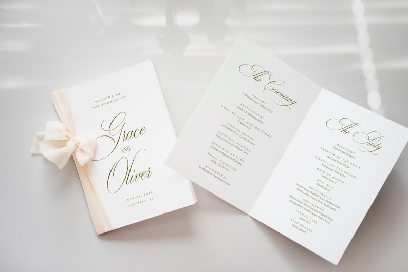 Puede incluir: Programas de boda con caligraf&iacute;a elegante. Un programa est&aacute; cerrado con una cinta crema, el otro est&aacute; abierto, mostrando los detalles de la ceremonia y la fiesta. El texto dice "Grace and Oliver" y la fecha.