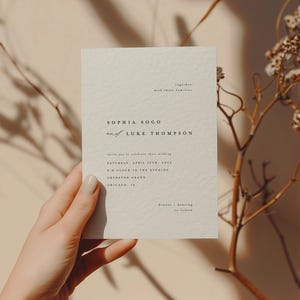 May include: A minimalist wedding invitation card with a cream background and black text. The card reads "Sophia Sogo and Luke Thompson" with the wedding date and time. The invitation states "Saturday, April 15th, 2023, 5 o'clock in the evening, The Sheraton Grand, Chicago, IL."