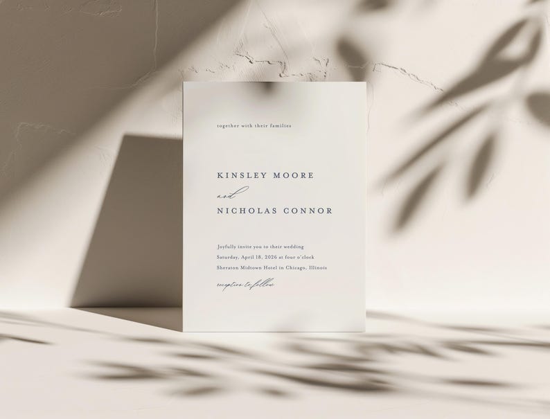 Op de afbeelding: Een witte huwelijksuitnodigingskaart met de tekst "Kinsley Moore en Nicholas Connor" en details over hun huwelijksceremonie. De kaart ligt op een witte, textuurrijke achtergrond met schaduwen.