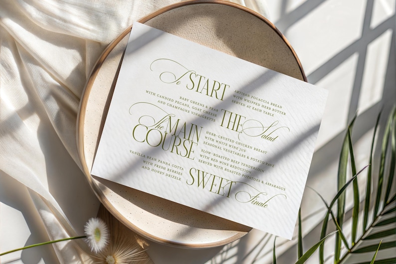 Pode incluir: Um cart&atilde;o de menu de casamento com uma elegante escrita verde-oliva, listando pratos como "Come&ccedil;o", "Prato principal" e "Final doce". O cart&atilde;o repousa sobre um prato bege, com um tecido branco e sombras no fundo.