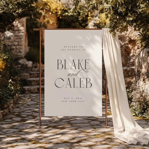 May include: A white wedding sign with a copper frame, announcing the wedding of Blake and Caleb on 9 May 2026 in New York City.