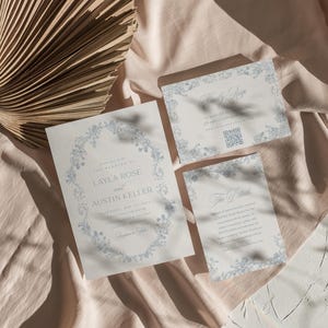 May include: Wedding invitation suite with a floral design in blue and white. The invitation card features the text "Please join us for the wedding of Layla Rose and Austin Keller". The RSVP card has the text "Kindly RSVP" and a QR code. The details card has the text "The Details".