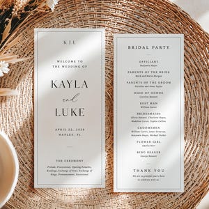 May include: Two wedding programs with text, including the names "Kayla and Luke" and "Bridal Party." The programs are on a woven, light brown surface, with dried flowers and a white bowl in the background.