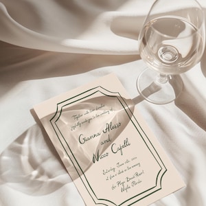 May include: A peach-colored wedding invitation with a dark green border. The invitation reads "Together with their families joyfully invite you to the wedding of Gianna Alesso and Nicco Capelli Saturday, June 18th, 2022 at five o'clock in the evening La Playa Beach Resort Naples Florida"