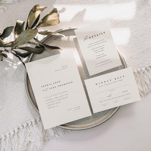 May include: A set of three white wedding invitation cards with black text. The main card reads "Sophia Soo & Luke Thompson". The second card reads "Details" and the third card reads "Kindly RSVP".
