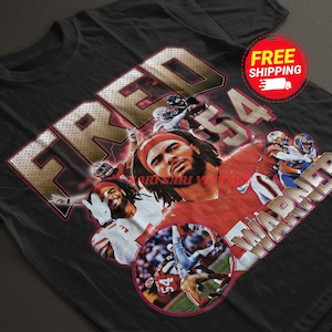 May include: Black t-shirt with a graphic print of football player Fred Warner, number 54, in a red and white uniform. The text "FRED WARNER" is printed in gold on the shirt.