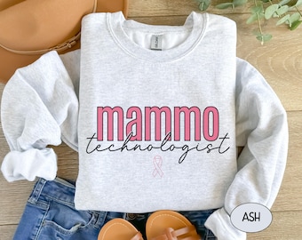 May include: A gray sweatshirt with the text "mammo technologist" in pink and black lettering. A pink ribbon is below the text.