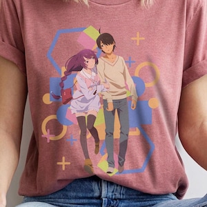 May include: Heather mauve t-shirt featuring a colorful graphic of two anime characters. The design includes a geometric background with pastel colors. The shirt has short sleeves and a crew neck.